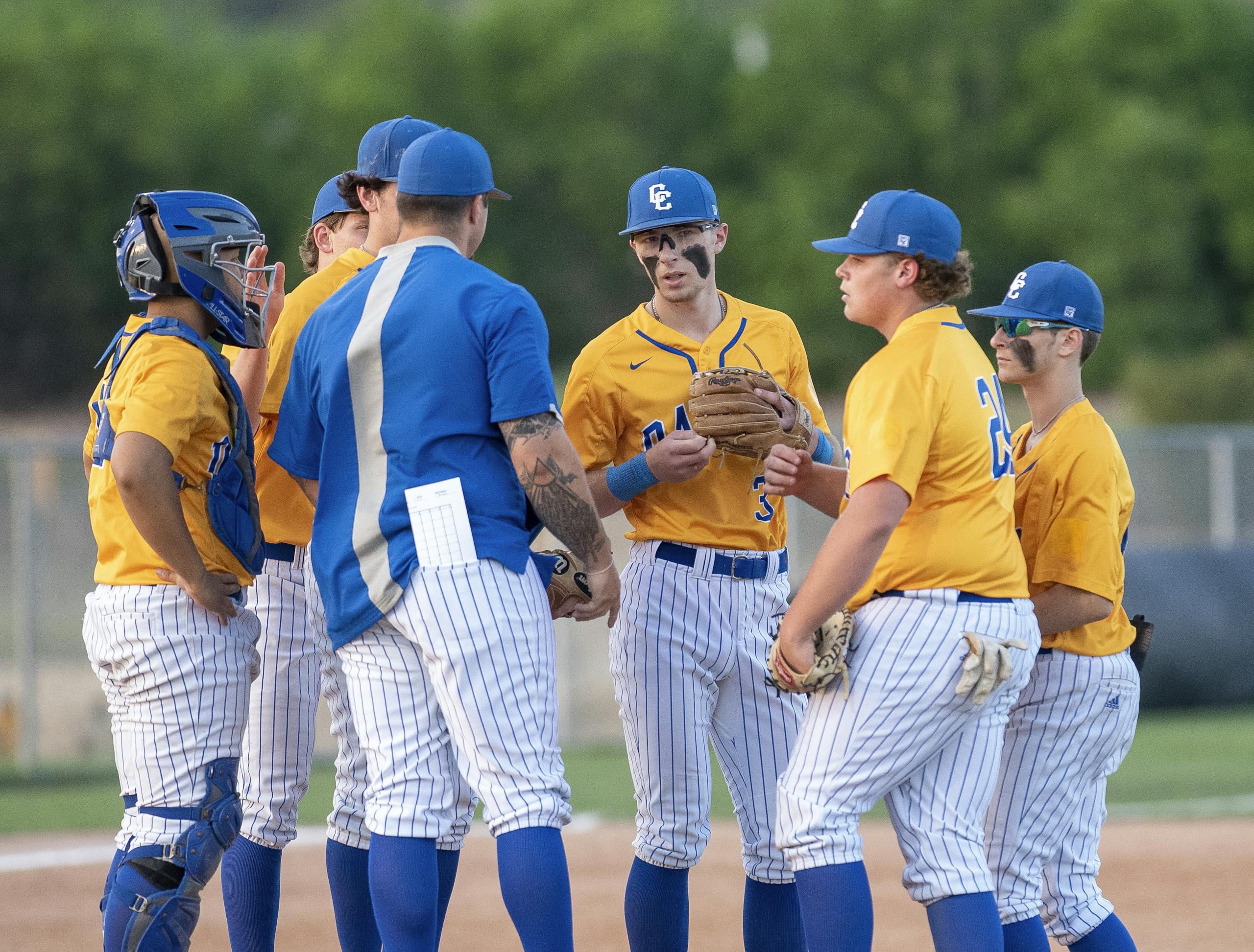 High school baseball players in Copperas Cove, Texas strategize during a game, wearing blue and yellow uniforms.